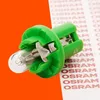 A close-up product shot of a green plastic-based light bulb with a clear glass bulb, set against a split orange and white background with repeating text. Produktbild-Vorschau