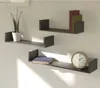 Three modern, dark gray U-shaped shelves mounted on a light gray wall. The top shelf holds a white pot with a green plant. The middle shelf has three books in red, green, and gray. The bottom shelf has a blue book and a round clock with a wooden frame. Voir les images du produit