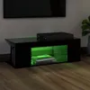 A modern black TV stand with green LED lighting, placed on a wooden floor in front of a wall. A television is visible at the top of the image. Voir les images du produit