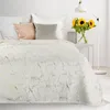 A neatly made bed with a white blanket featuring a gold marble pattern, accented by decorative pillows and a vase of sunflowers on a side table. Anteprima dell’immagine prodotto