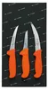 Three knives with orange handles are laid out on a black background with a repeating arrow and text pattern. Náhľad obrázku produktu