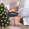 A person is holding a wallet with credit cards inside, with a decorated Christmas tree in the background. Anteprima dell’immagine prodotto