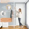 A woman is assembling a white telescopic coat rack in a room with a door and a bed. The coat rack is shown with instructional diagrams and text. Produktbild-Vorschau