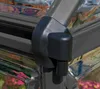Close-up of a black plastic clip attached to the corner of a grey aluminum frame of a greenhouse, with reflective panels and pink flowers visible in the background. Produktbild-Vorschau