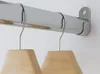 A close-up view of a chrome-plated wardrobe rail with two wooden hangers attached. Produktbild-Vorschau