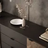 A close-up view of a black dresser with a marble plate and a vase with dried flowers on top. The dresser has gold accents and a patterned wooden door. Produktbild-Vorschau