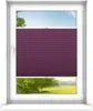 A window with a purple pleated blind partially covering the view of a green landscape with trees and a blue sky. Produktbild-Vorschau