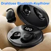 A close-up shot of black wireless earbuds and their charging case, placed on a textured fabric surface. Produktbild-Vorschau