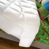 A close-up view of a white comforter on a bed, with a colorful patterned quilt and pillows visible. Produktbild-Vorschau