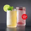Two frosted glasses filled with colorful drinks, one garnished with lime and mint. Voir les images du produit
