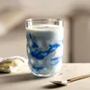 A glass of drink with blue swirls, next to a napkin and spoon. Anteprima dell’immagine prodotto