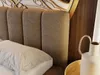 A close-up view of a bed with a textured headboard and a white pillow. Produktbild-Vorschau