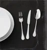 A place setting with a plate, fork, knife, and spoon on a black placemat. Podgląd zdjęcia produktu