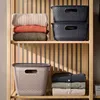 Storage baskets and folded clothes on a wooden shelf. Produktbild-Vorschau