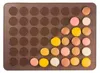 A top-down view of a brown silicone baking mat filled with colorful macarons. Podgląd zdjęcia produktu