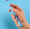 A hand holding a blue interdental brush with a pink tip against a blue background. Produktbild-Vorschau