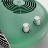 A close-up view of the top of a green electric heater, showing two silver control knobs and the fan grille. Podgląd zdjęcia produktu