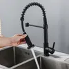 A person is using a black kitchen faucet with a pull-down sprayer over a double stainless steel sink. Náhľad obrázku produktu