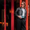 A man stands in front of a red doorway, holding a teal cassette player. Náhled obrázku produktu