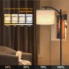 A floor lamp with a fabric shade is shown in a living room setting, next to an armchair. The image also displays a graphic illustrating different color temperatures and brightness levels. Voir les images du produit