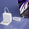 A white laptop charger is plugged into a wall socket and connected to a laptop. Podgląd zdjęcia produktu