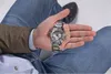 A person is holding a watch in their hand. Náhled obrázku produktu