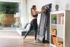 A woman is folding a treadmill in a living room. Produktbild-Vorschau