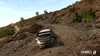 A rally car driving on a dirt road on a hillside. Produktbild-Vorschau
