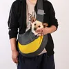 A person is holding a dog in a sling-style pet carrier. Produktbild-Vorschau