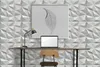 A modern home office setup with a desk, laptop, lamp, and framed artwork against a textured wall. Anteprima dell’immagine prodotto