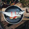 A whole fish is prepared in a pan with lime and chili slices, ready for cooking. Voir les images du produit