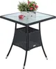 A black polyrattan table with a glass top, a red candle, and a potted plant. Produktbild-Vorschau