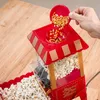A hand pouring popcorn kernels into a red popcorn machine. Náhled obrázku produktu