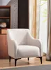 A light-colored armchair sits in a room with wooden furniture and curtains.