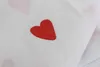 A close-up of white fabric with red heart patterns. Produktbild-Vorschau