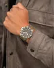 A close-up shot of a man's wrist wearing a watch, with his hand resting on a jacket. Podgląd zdjęcia produktu