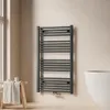 A modern bathroom setting with a towel warmer, a stool with a towel, and a bathtub. Náhled obrázku produktu