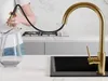 A person is filling a glass pitcher with water from a gold kitchen faucet. Produktbild-Vorschau