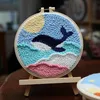 A punch needle embroidery kit featuring a whale in the ocean, displayed on a small wooden easel. Produktbild-Vorschau