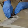 Hands wearing blue gloves cleaning a car seat with a brush and foam. Anteprima dell’immagine prodotto