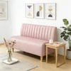 A pink sofa is placed in a room with artwork on the wall and a small side table next to it. Anteprima dell’immagine prodotto