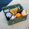 A green Stanley lunch box filled with food and drinks, placed on a concrete surface next to water. Podgląd zdjęcia produktu