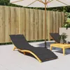 Two black chaise lounge cushions are placed on a patio next to a wooden fence and an umbrella. Anteprima dell’immagine prodotto