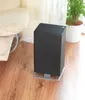 A black air purifier sits on a wooden floor next to a cream-colored armchair and a potted plant. Podgląd zdjęcia produktu