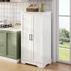 A white kitchen cabinet with two doors stands next to a window in a kitchen setting. Voir les images du produit