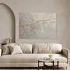 A painting of branches with gold accents is displayed above a sofa in a living room. Produktbild-Vorschau