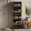 A tall, narrow shoe cabinet with multiple flip-down drawers is shown in a room with a door and a mirror in the background. Several pairs of shoes are visible inside the drawers. Anteprima dell’immagine prodotto