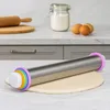 A stainless steel rolling pin with adjustable thickness rings is shown on a marble countertop, with a wooden rolling pin, a jar of flour, and eggs in the background. Produktbild-Vorschau
