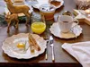 A festive breakfast setting with a fried egg, toast, orange juice, and coffee, decorated with small deer figurines and greenery. Produktbild-Vorschau