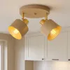 A beige and gold ceiling light fixture with two adjustable spotlights is shown mounted on a white ceiling above kitchen cabinets. Produktbild-Vorschau